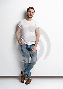 Full length studio portrait of casual young man in jeans and shirt. Isolated on white background.