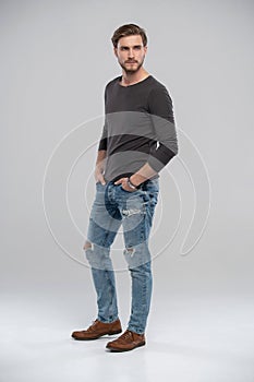 Full length studio portrait of casual young man in jeans and shirt. Isolated on white background.