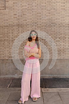 In full length stylish young caucasian woman looking at camera stands at street during day.