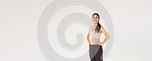 Full length of sweaty smiling fitness girl, female athelte in active wear looking pleased while workout, training in gym