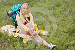 Full length of thoughtful female hiker sitting on grass