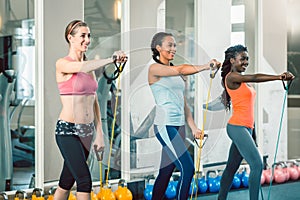 Full length of three fit women exercising with resistance bands