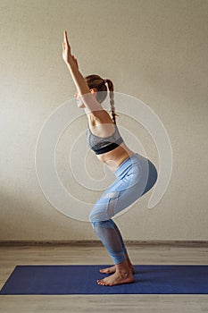 Full length vertical image. Young european woman wearing sport clothes doing workout at home exercising doing yoga home fitness