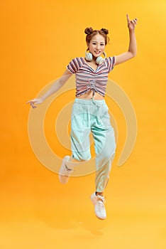 Full length view of nice girl jumping listening audio mp3 technology virtual connection isolated on bright yellow color background