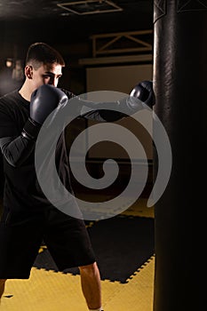 Full length view of young male boxer training with punching bag in he gym