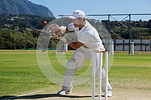 Full length of wicketkeeper catching cricket ball behind stumps