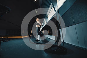 Full length wide angle shot of a woman performing rope climbs at the gym