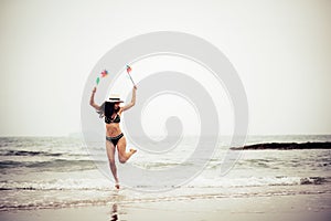 Full Length Of Woman Holding Pinwheel Toys While Jumping At Beach