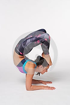 Full length Woman practicing yoga Vrschikasana, Scorpion pose