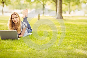 Full length of woman using laptop while lying on grass