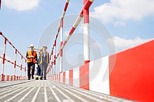 Full-length of workers walking on footbridge against sky