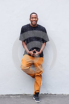 Full length young african man standing against gray wall