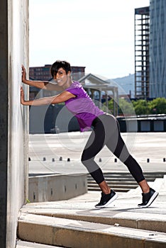 Full length young african woman doing stretching workout outdoors