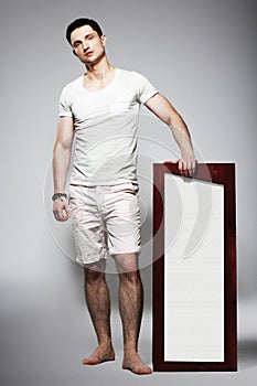 Full Length of Young Barefoot Man in White Shorts with Plackard