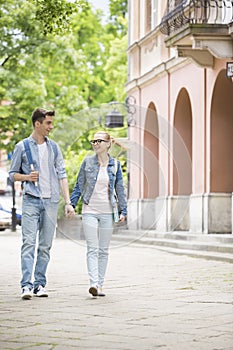 Full length of young college couple talking while walking in campus