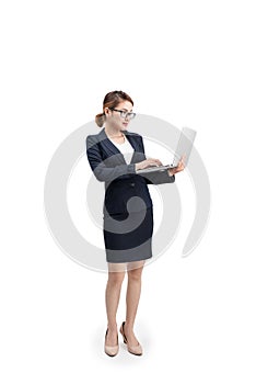 Full length of a young female businesswoman holding laptop over grey background.