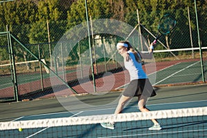 Full length of young female caucasian tennis player hitting ball at court on sunny day