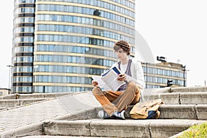 Full length of young male college student reading book against building