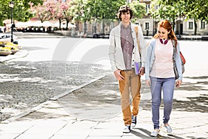 Full length of young male and female college students walking on footpath