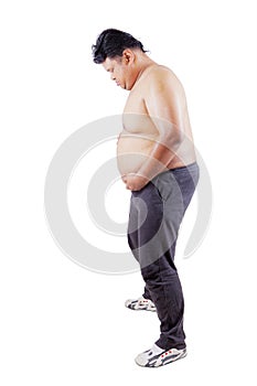 Full length of a young man holding his fat belly