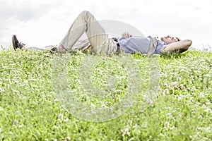 Full length of young man lying on grass against sky