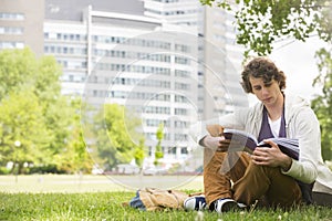 Full length of young man reading book on college campus