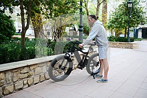 Full length of young man renting an electric bike for riding in the city. Electric bicycle - public eco transport