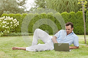 Full length of young man using laptop while reclining in park