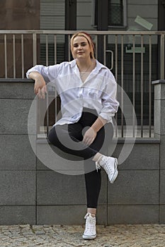 Full Length Young Real Beautiful Brown Haired Woman In Jeans And T-shirt Sitting On Stone