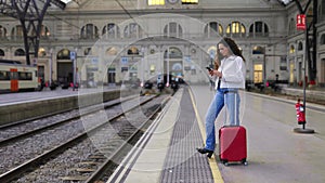 Full length of young traveler woman using phone at train station