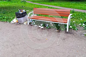 Full litter bin in the park next to the bench