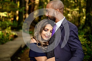 Full of love photo of an affectionate mixed race young couple holding each other in the woods