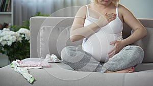 Full of maternal instincts woman gently touching her beloved pregnant tummy