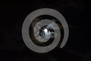 A full moon with clouds in the black night sky