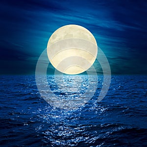 Full moon in clouds over water