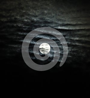 Full moon with dramatic clouds and lunar halo vertical