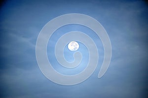 A full moon glowing in a night sky with clouds