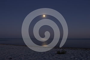 Full moon with moonlight on calm sea surface, long exposure. Island beach in the night. Moon path on sea. Twilight on seacoast.