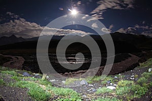 Full moon Night with beams over big mountain glade with river.