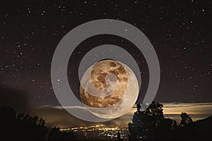 Full moon at night with stars, with lights from city view from highland mountain