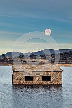 Full moon over partially submerged stone building in Corsican la