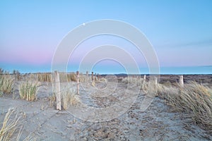 Full moon over sand path with fence in dunes