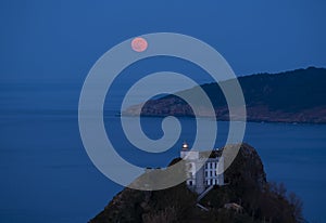 Full moon over the sea and silver lighthouse on Mount Ulia, Euskadi photo