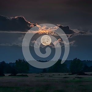 Full moon peeks through dark clouds, casting an eerie glow