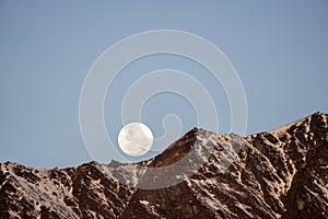 Full Moon rise over the mountains on the blue sky background