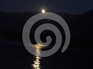 The full moon rises over Lake Iseo in front of the town of Lovere