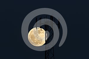 Full moon rising behind cell phone tower