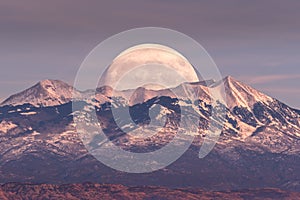 Full moon rising behind La Sal Mountains in Canyonlands National Park during sunset