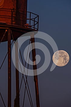 Full moon rising behind water tower