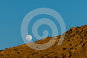 Full moon rising over mountainside photo